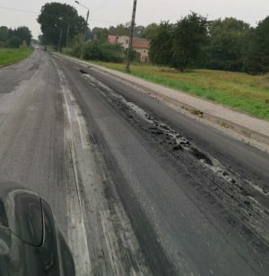 Na zdjęciu widoczny zaśmiecony warstwą błota odcinek drogi asfaltowej.