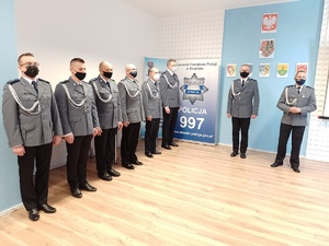 Na zdjęciu widoczni ubrani w mundury galowe policjanci w trakcie uroczystości. Zdjęcie wykonane wewnątrz pomieszczenia.