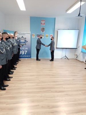 Na zdjęciu widoczni ubrani w mundury galowe policjanci w trakcie uroczystości. Zdjęcie wykonane wewnątrz pomieszczenia.