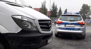 Na zdjęciu widoczny pojazd dostawczy, w drugim planie radiowóz oznakowany.