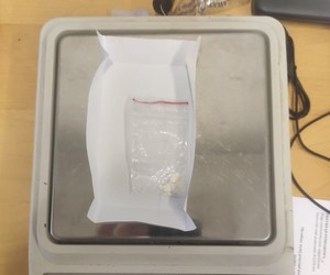 Na zdjęciu widoczny biały proszek (narkotyk - amfetamina) w torebce foliowej odłożony na wadze elektronicznej.