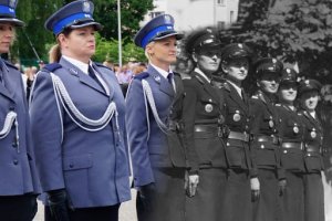 Na zdjęciu widoczne umundurowane policjantki stojące w szeregu na tle flagi Polski.