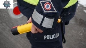 na zdjęciu widoczny umundurowany policjant ruchu drogowego, który w ręku trzyma tarczę &quot;lizak&quot; służącą do zatrzymywania pojazdów oraz przenośne urządzeni do kontroli stanu trzeźwości.