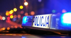 Naz zdjęciu widoczny podświetlony napis Policja na ciemnym tle.