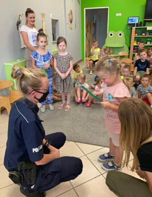 Na zdjęciu widoczna grupa dzieci w obecności umundurowanych policjantów. Zdjęcie wykonane w pomieszczeniu.