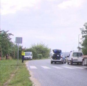 Na zdjęciu widoczny radiowóz oznakowanego tuż obok pojazd dostawczy koloru jasnego. W tle umundurowani policjanci wykonujący czynności służbowe.